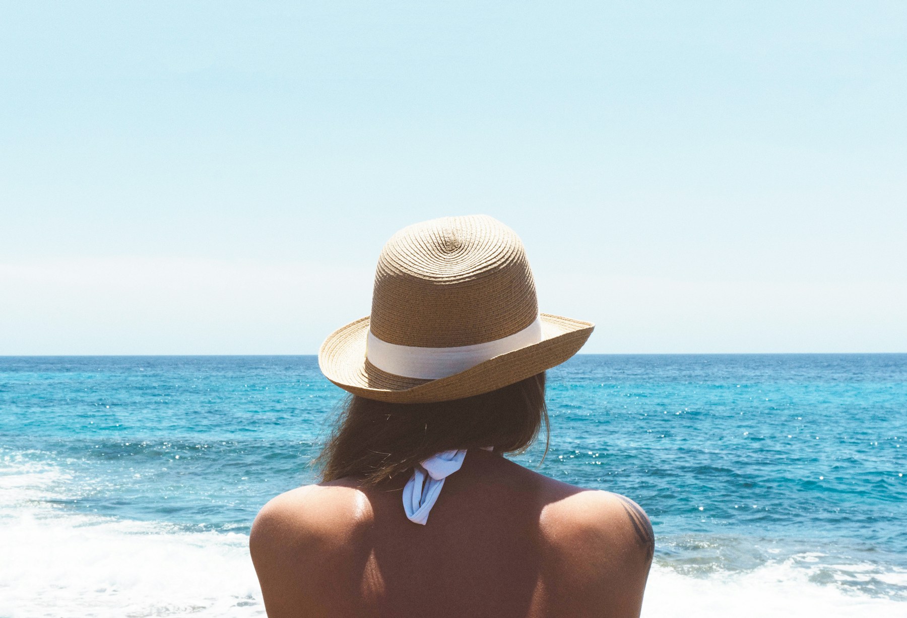Mujer con sombrero frente al mar