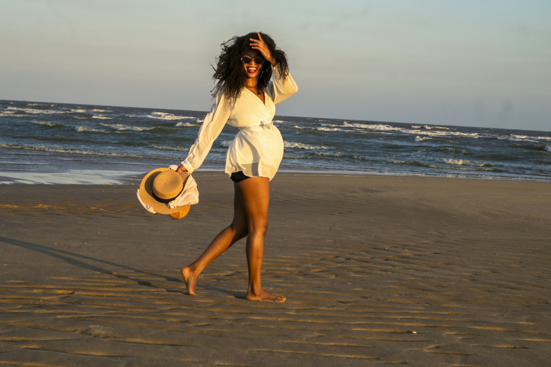 Mujer con vestido blanco y sombrero en la playa