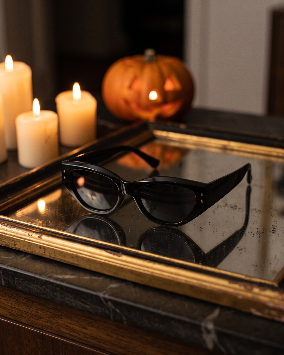 Lentes de sol negros sobre un espejo antiguo con velas
